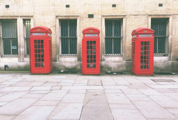 red telephone booth beside brown concrete building